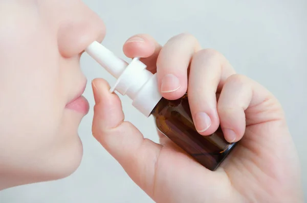 Burun spreyi. Güzel ve genç birbayan. Burun damlaları ile karşı karşıya. Kadın püskürtme tıbbi burun spreyi burnundaki close-up. Soğuk algınlığı ve grip, sağlık kavramı. Portre.