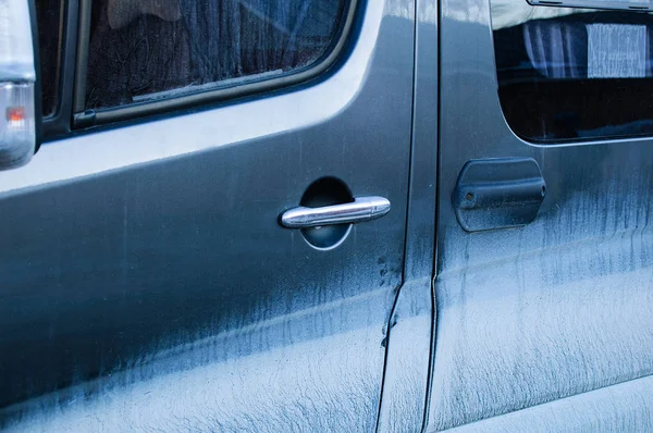 Dirty blue car door. Dirty glass. Dry dirt. Close-up.