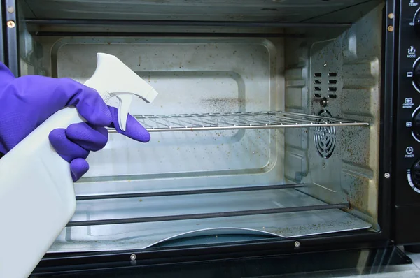 Ev hanımı. Kirli fırın. Temizlik maddesi ile el mavi koruyucu eldiven.