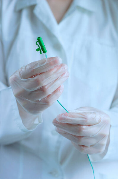 Urological catheter in the hands of a doctor. Close-up.Vertical photo.