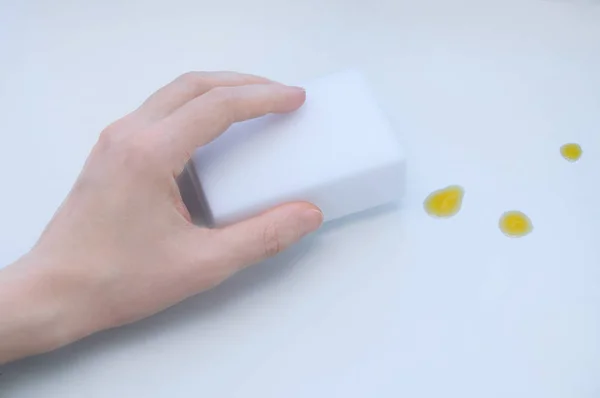 Bir kız elinde Melamin beyaz sünger. Beyaz bir tablodaki kiri temizler.