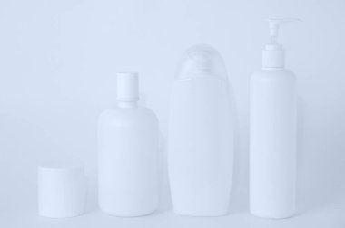 Beyaz arka planda kozmetik ürünleri olan beyaz plastik şişeler.