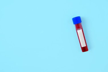 Mavi arka planda plastik bir test tüpündeki kan. Yukarıdan görüntüle.