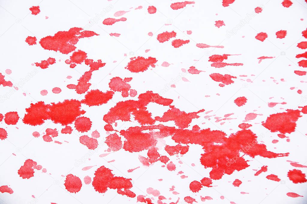 Drops and splashes of red paint on a white background close-up.