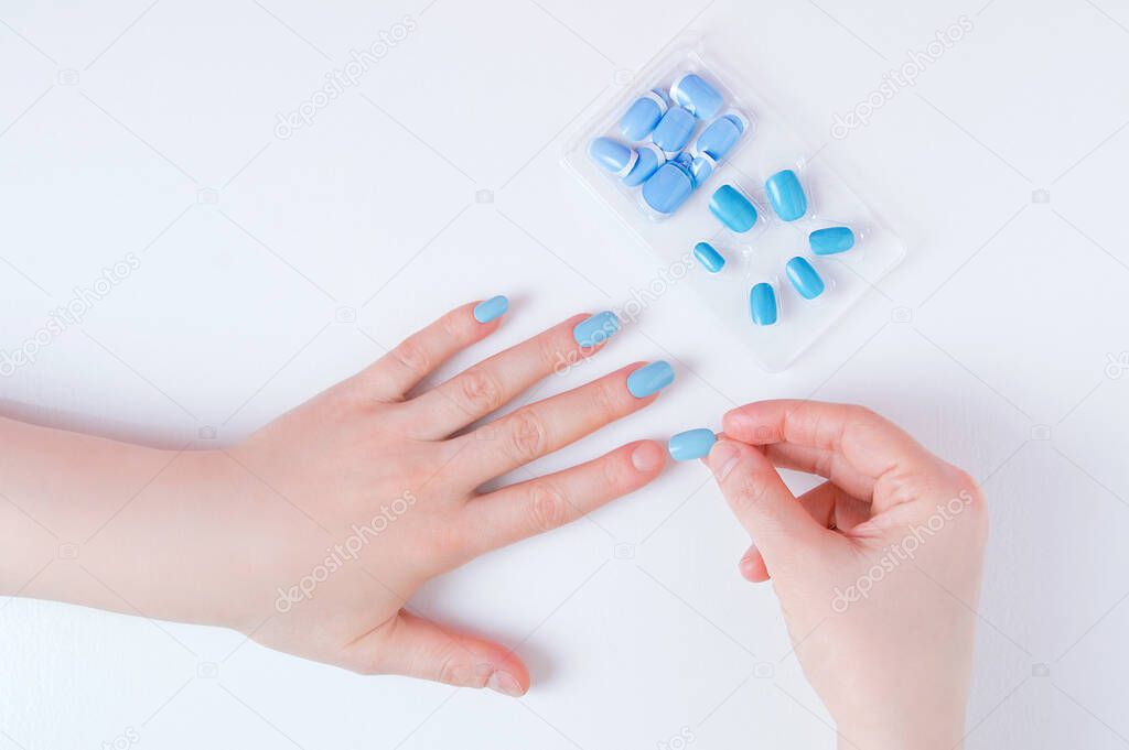 Manicure on a woman hand with false nails on a white background.