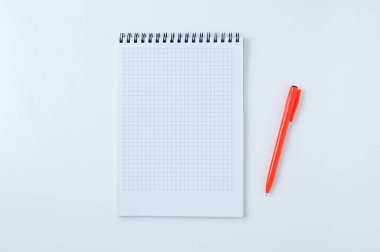 Hücre yayında not defteri ve beyaz arka planda turuncu bir kalem. Yukarıdan görüntüle.