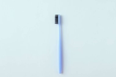 Beyaz arkaplanda siyah tüylü mavi diş fırçası.