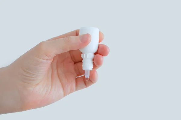 Göz beyaz bir şişeye düşer, yakın plan bir elde. Beyaz arkaplan.