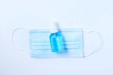 Tıbbi maske ve dezenfektan sprey şişesinde. Beyaz arkaplan.