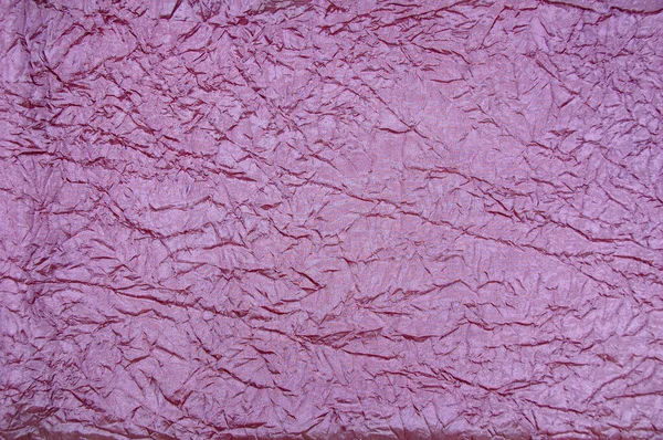 Dusty pink crinkled fabric texture close up.