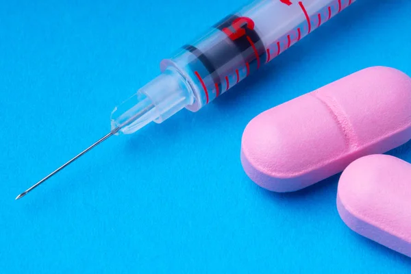 1ml insuline spuiten en roze pillen op een blauwe achtergrond. omega3. — Stockfoto