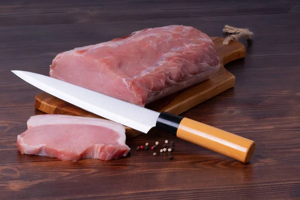 Raw pork on cutting board with pepper and japanese knife. Royalty Free Stock Photos