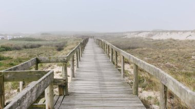Sisli bir sabah Costa Nova Beach ahşap yaya köprüsü. Aveiro, Portekiz