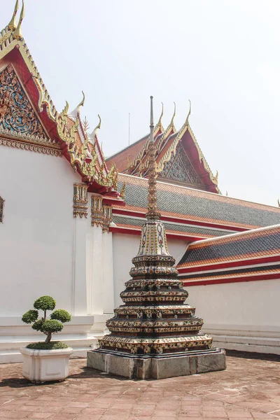 Bonsai árvore ao lado de pequena estupa com Wat Pho templo como fundo. Bangkok, Tailândia . — Fotografia de Stock