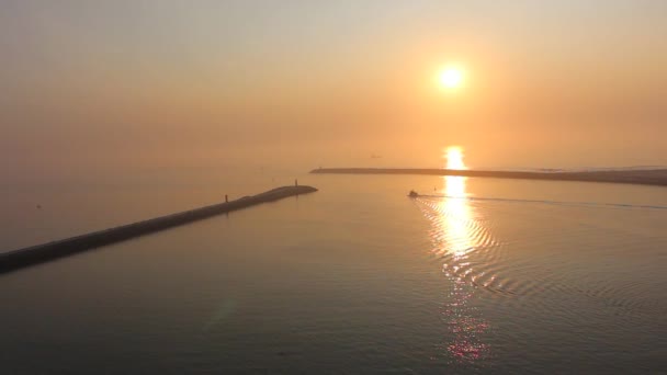 Ensam båt sakta lämnar hamnen och segling i solnedgången i fredlig ocean. — Stockvideo