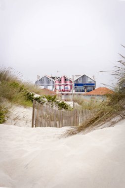 Çok güzel ve şirin plaj evleri Beach kumulları gördün. Plaj evleri Costa Nova, Portekiz üzerinden renkli çizgili.