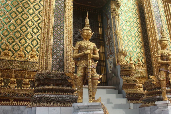 Estátuas gigantes de ouro guardando a porta maciça de Phra Mondop no templo de Wat Phra Kaew em Bangkok, Tailândia . — Fotografia de Stock