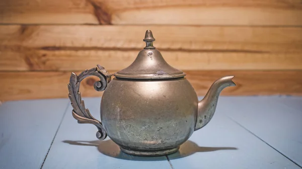 Beautiful vintage copper teapot kettle with tarnished metal, sitting in blue wooden surface. Old teapot with abrasions. — Stock Photo, Image