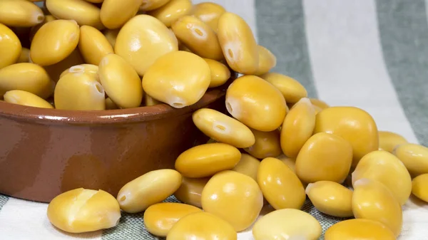 Makro bir toprak kase tuzlu lupin fasulye, üstüne bir soyulmuş gri kumaş havlu ile ağzına kadar dolu için.