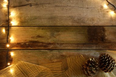 Noel ışıkları, çam kozalakları ve altın geniş şerit şerit rustik ahşap tablo düz yatıyordu. Kopya alanı ile.