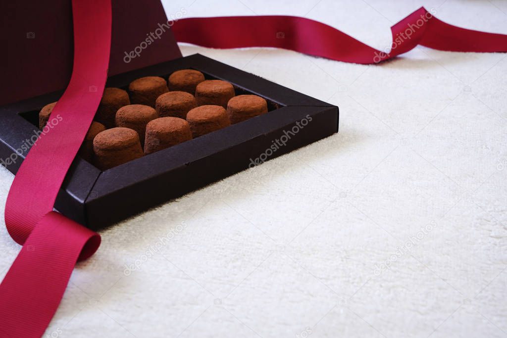 Close up of elegant black box of chocolate truffles, with red ribbon. Valentines Day or romantic celebration concept.