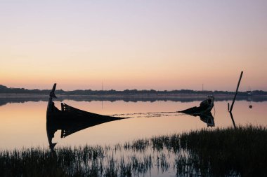 Aveiro Lagünü kıyısına yakın bozulmuş ve batık tekne, bir gün batımında.