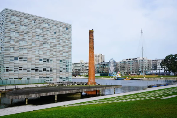 Aveiro, Portugal - December 2018: View of Melia Ria Hotel and old terracotta chimney. With Ferris wheel in the distance. Stock Image