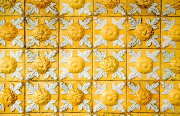 Staré a špinavé, jasně žluté reliéfní dlaždice s květinovými vzory. Textura, dlaždice a pozadí z glazované keramiky. — Stock fotografie