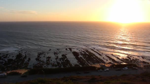 Delikatne fale oceanu na skalistym brzegu podczas zachodu słońca, widziane z punktu widokowego w Cabo Mondego, w Portugalii. — Wideo stockowe