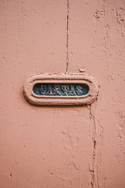 Vintage Portuguese Mail Slot with beautiful lettering, in wooden door with cracked and peeling pastel paint.