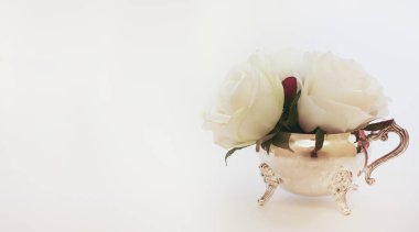 Gümüş krema kabının içinde izole edilmiş beyaz çiçekler. Kopya alanı olan ikindi çayı konsepti