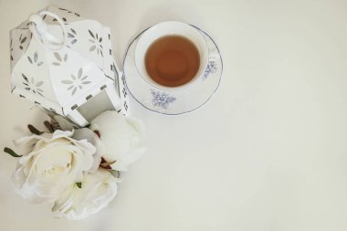 Beyaz gül buketi, bir mum feneri ve yumuşak arka planda güzel bir çay fincanı. Öğleden sonra çayı için kavram. Boşluğu kopyala