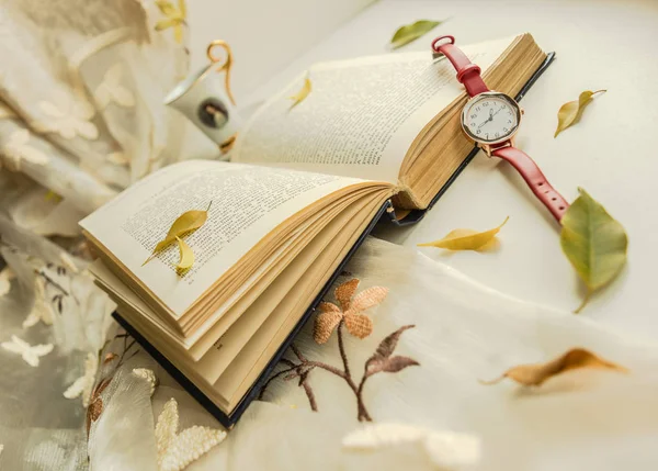Sonbahar natürmort penceresinde. Bir kitap, saat ve yaprakları ile sonbahar natürmort.