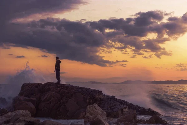 a beautiful sunset on the sea, a man stands on a rock, a man talking to the sea, sky and ocean