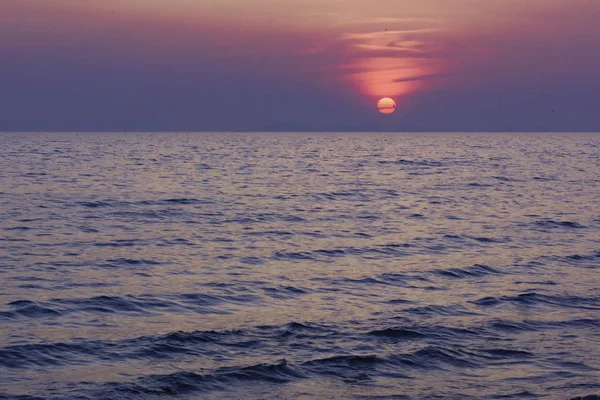 Güneş deniz ufkunun üzerinden batıyor. Denizde gün doğumu. Leylak güneşi