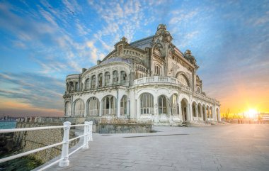 The abandoned casino in Constanta, Romania under the fiery sky at sunset / dusk. Top sightseeing of the Black sea located city clipart