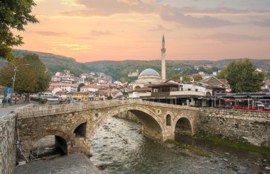 Prizren, Kosova - 08 Temmuz 2019: Eski taş köprü ve eski Osmanlı Sinan Paşa Camii 'nin günbatımı. Bistrica nehrinin kıyısında tarihi bir şehir.
