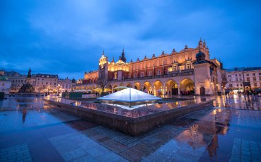 Krakow, Polonya. Polonya 'nın Krakow şehrinin ana meydanında gece aydınlanan Kumaş Salonu Sukiennice binası güzel ışıklarla aydınlandı.