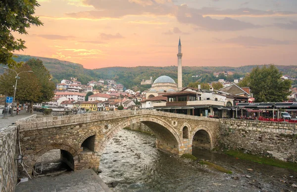 Prizren, Kosova - 08 Temmuz 2019: Eski taş köprü ve eski Osmanlı Sinan Paşa Camii 'nin günbatımı. Bistrica nehrinin kıyısında tarihi bir şehir.