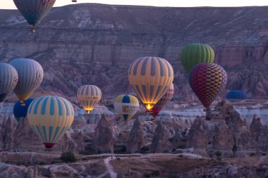 Goreme, Kapadokya, Türkiye. Goreme Ulusal Parkı 'nda güzel manzaralar. Yüzlerce renkli sıcak hava balonu gün doğumunda gökyüzünde uçuşuyor. Vadide inanılmaz kaya oluşumları