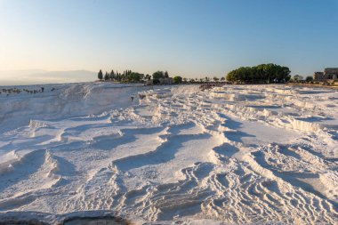 Pamukkale 'de güzel gün batımı ve doğal travertin havuzları ve terasları. Denizli yakınlarındaki Türkiye 'nin güneybatısındaki pamuk şatoda sıcak su, turkuaz mavisi bir su ile bembeyaz renklendiriliyor.