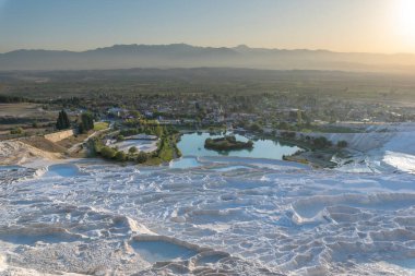 Pamukkale 'de güzel gün batımı ve doğal travertin havuzları ve terasları. Denizli yakınlarındaki Türkiye 'nin güneybatısındaki pamuk şatoda sıcak su, turkuaz mavisi bir su ile bembeyaz renklendiriliyor.