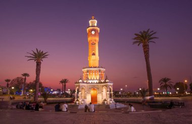 Konak Meydanı sokak manzaralı eski saat kulesi (Saat Kulesi) gece gün batımından sonra. 1901 yılında inşa edilmiş ve İzmir 'in resmi sembolü olarak kabul edilmiştir.. 
