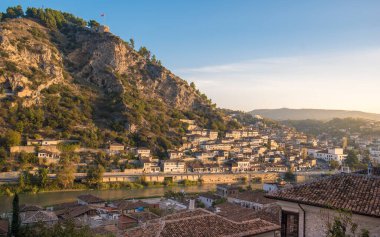 Tarihi şehrin panoraması. Arnavutluk 'un Berat eski kentinde (mangalem semtinde) güneş doğarken geleneksel sedir evleri. UNESCO 'nun dünya mirası listesinde Osum nehri kıyısında yer alıyor. bin pencere