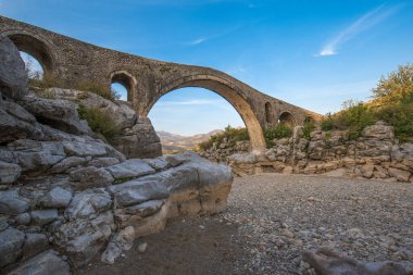 Arnavutluk 'un Mes kentindeki Mesi Köprüsü' nün (Ura e Mesit) Panoraması. Eski bir Osmanlı köprüsü - ülkenin en büyüğü. Güzel kuru nehir ve dağların manzarası.