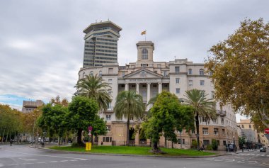 Barcelona, Spain - 15 June, 2019: Building of the Military Base at the lower end of La Rambla as seen from The Columbus Monument and an office skyscraper Edifici Colon (also Torre Maritima) clipart