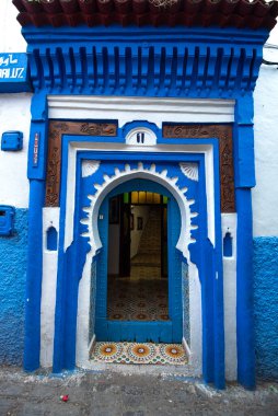Tipik, eski, karmaşık bir şekilde oyulmuş, çivili, Fas Riad kapısı, kapı çerçevesi ve eski ev. Medine 'deki mavi şehrin güzel manzarası. CHEFCHAOUEN, FOCCO 'da boyalı evler