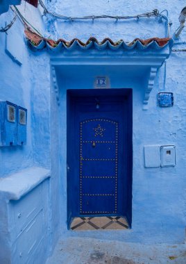 Tipik, eski, karmaşık bir şekilde oyulmuş, çivili, Faslı kapı ve çerçeve ve CheFCHAOUEN, Fas 'taki eski ev. Medine 'deki mavi şehrin güzel manzarası. boyanmış evler