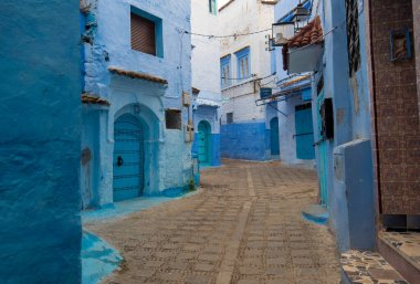 Mavi şehrin güzel manzarası CheFCHAOUEN, Medina 'daki MoroCCO. Geleneksel Fas mimari detayları ve boyalı evler. Kapısı olan bir sokak ve kemerli parlak mavi duvarlar