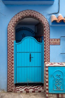 Tipik, eski, karmaşık bir şekilde oyulmuş, çivili, Faslı kapı ve çerçeve ve CheFCHAOUEN, Fas 'taki eski ev. Medine 'deki mavi şehrin güzel manzarası. boyanmış evler